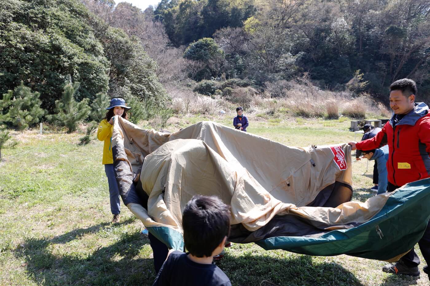 写真:テントを張る大人たちと手伝う子ども