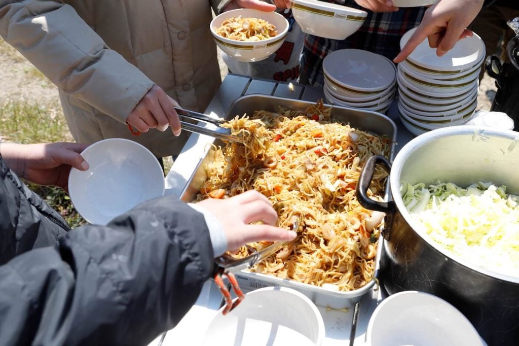 写真:大皿に乗った焼きそばをお皿に盛る様子