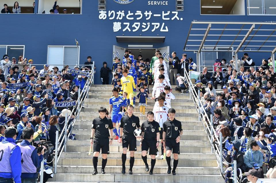 写真:「ありがとうサービス.夢スタジアム」に入場する選手、審判と、それを見守る大勢の観客