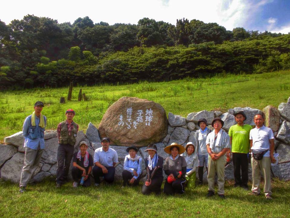 写真:「地球は子孫から借りているもの」と書かれた石碑の前に立つスタッフたち