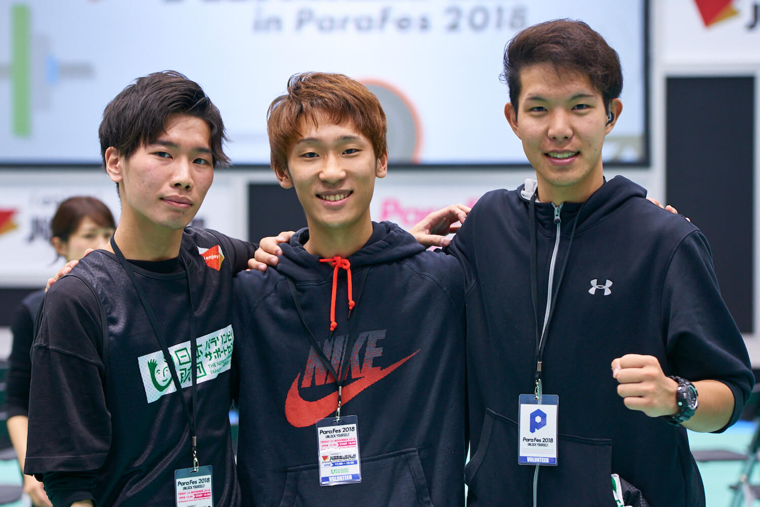 写真:肩を組みガッツポーズをとる3人のボランティア