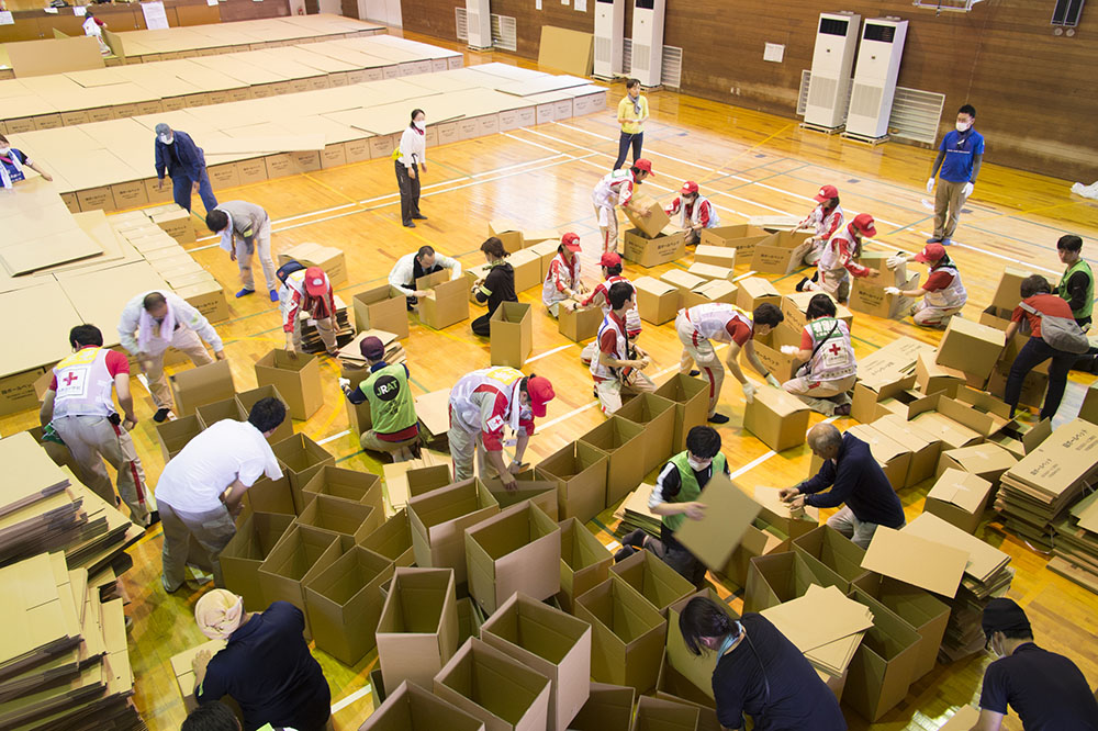 Photo of cardboard beds being set up in a gymnasium being used as an evacuation shelter