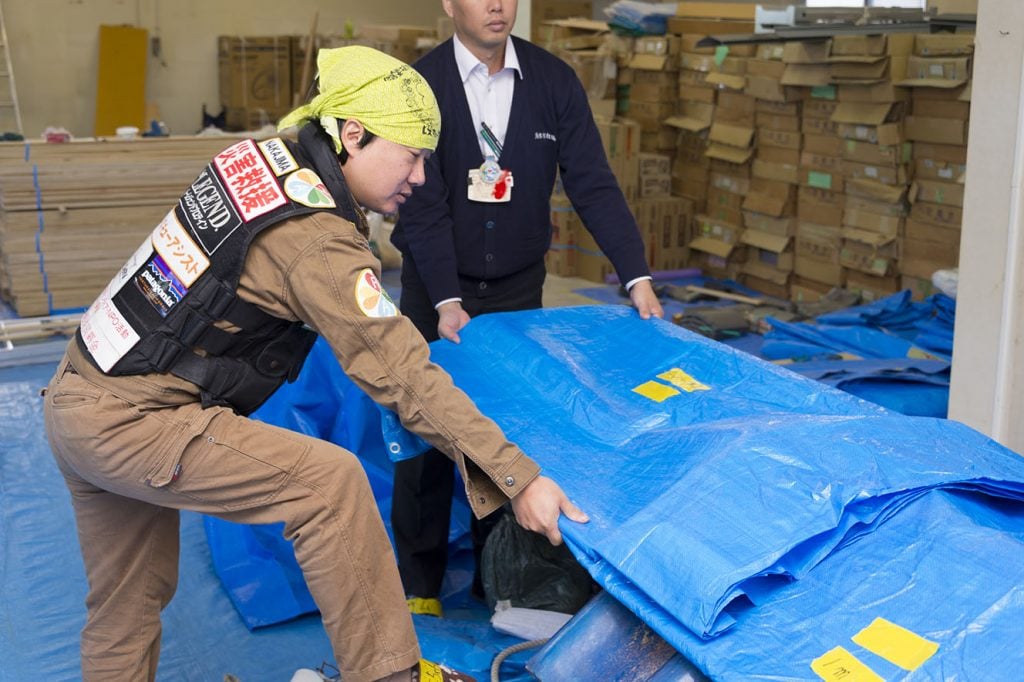 写真：ブルーシートを持ち作業する中島さん