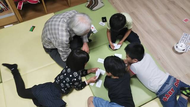 写真：カルタで遊ぶ子供たちとボランティア