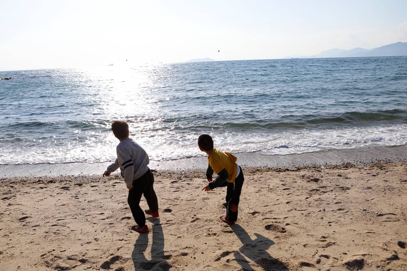 写真：海に向かって石を投げる子どもたち