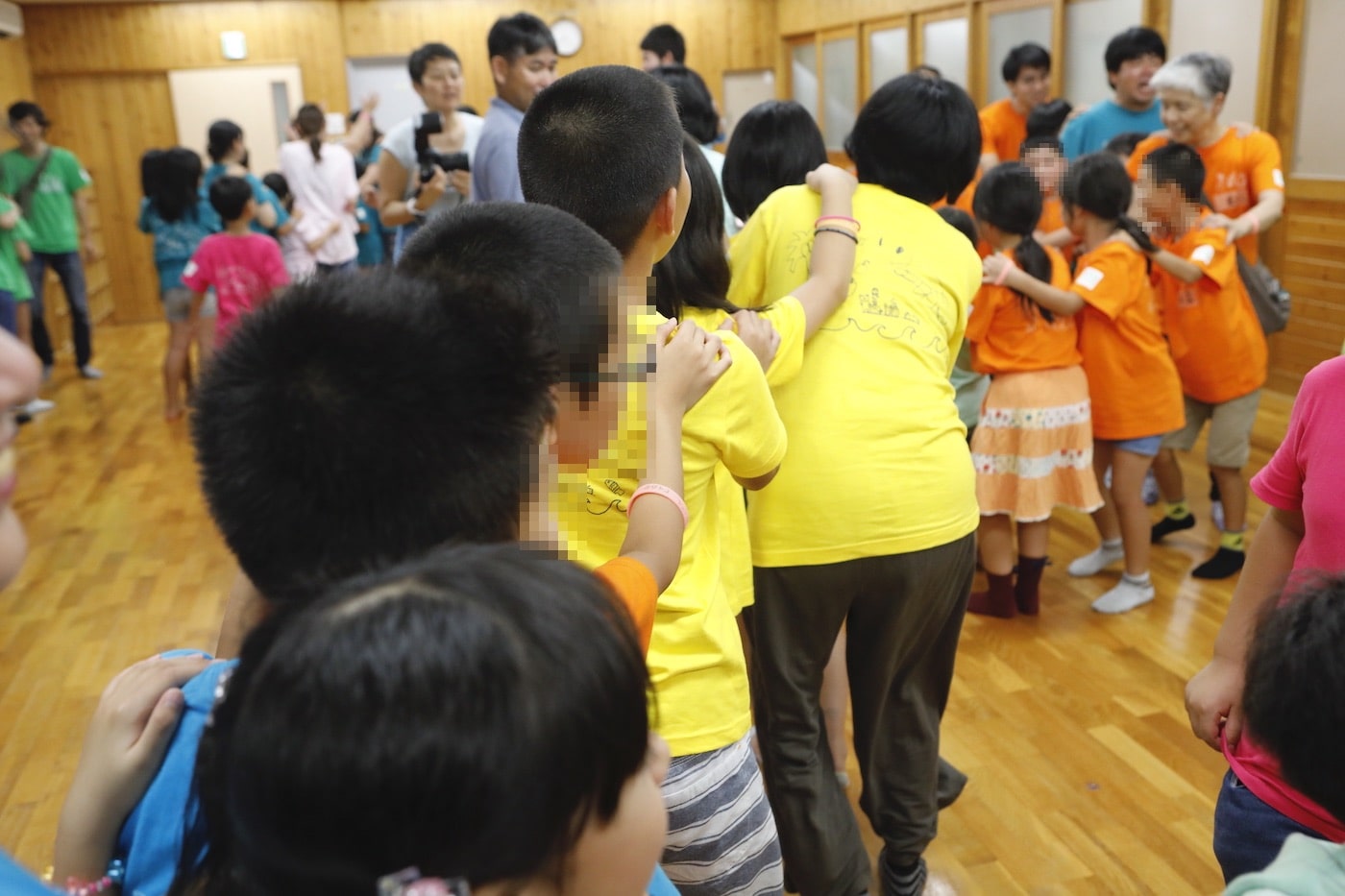 写真：ジャンケンゲームにより、長い列を組んで部屋の中を移動する大勢の大人や子どもたち