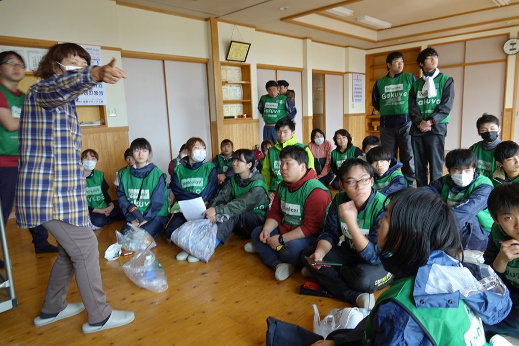 写真：公民館で昼休憩時に学生ボランティアに被災当時の様子を説明する鈴木さん 