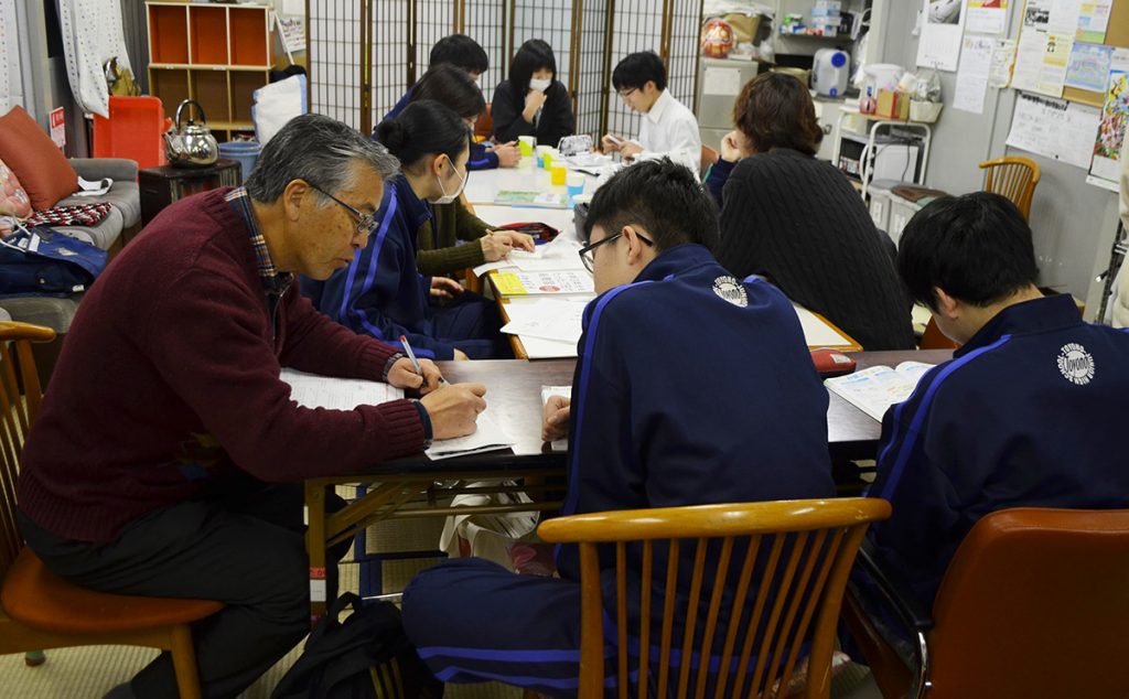 写真：中学生が机に座り、スタッフの指導を受けながら勉強をする様子