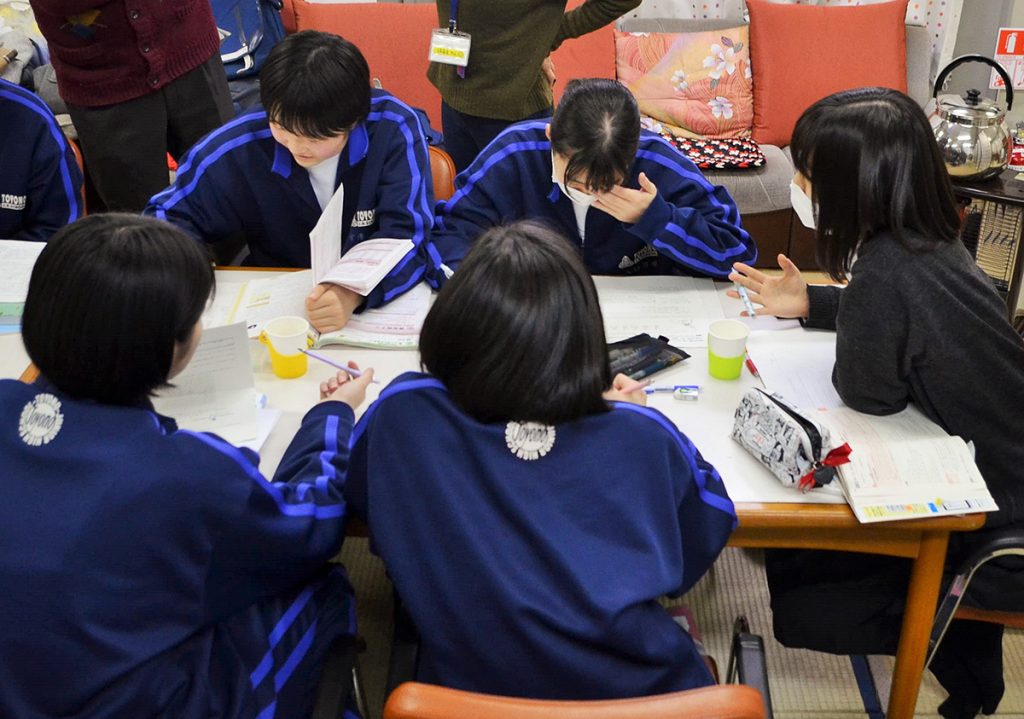 写真：自習室で机に座り、テキストを開いて勉強に取り組む中学生たち
