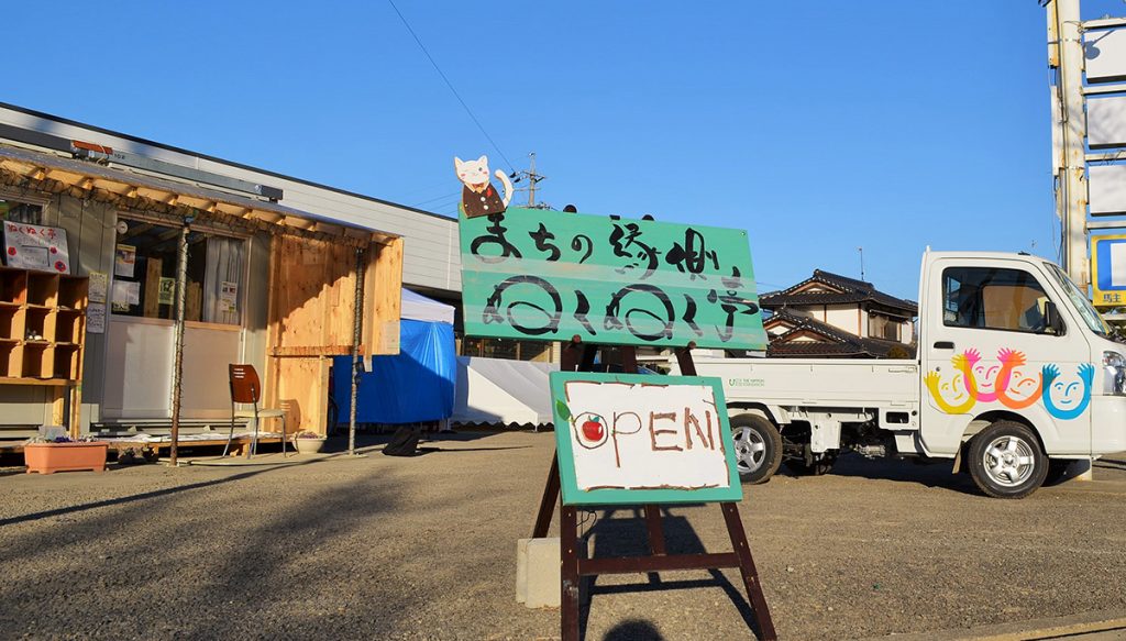 写真：駐車場を敷地として設けられたぬくぬく亭と看板。駐車場には日本財団が被災地に寄贈した軽トラックがありました