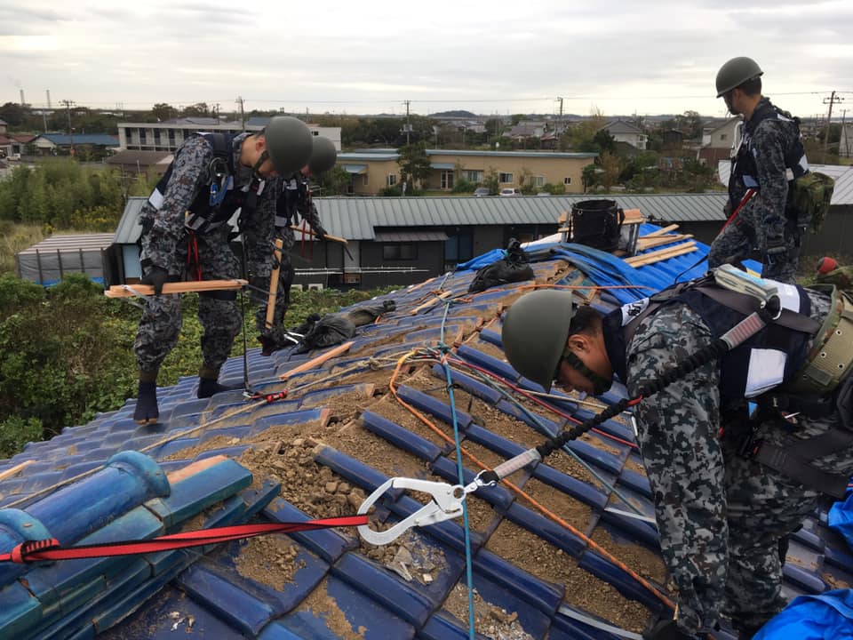 写真:被災した民家の屋根の上でブルーシートを張る自衛隊員の様子