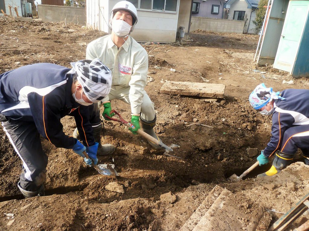 写真：スコップを手に、側溝にたまった泥を力をこめて掘り出す作業にあたる高校生の様子（12月14日、横沢祥子さん提供）