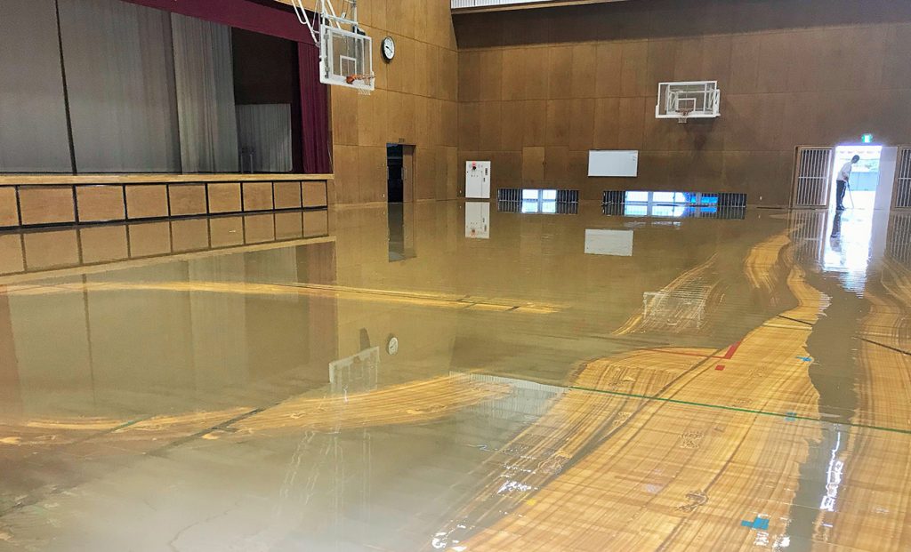 写真：体育館に泥水が入り、フロアの上に水がたまっている様子（10月13日、学校提供）