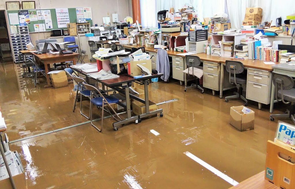 写真:校舎1階の職員室も浸水し、フロアに泥水がたまっています(10月13日、学校提供)