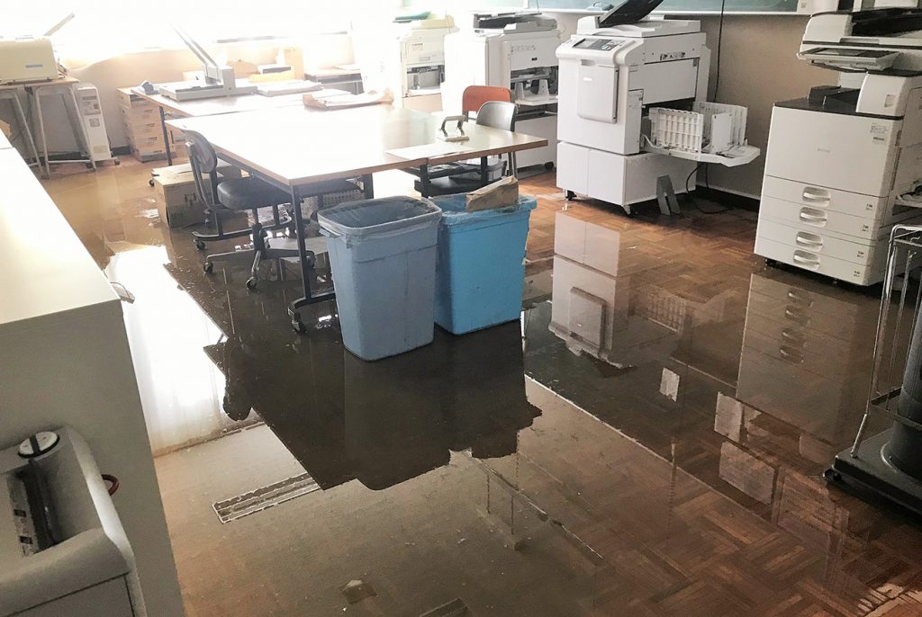 写真：コピー機のある部屋の床に水がたまっている様子（10月13日、学校提供）