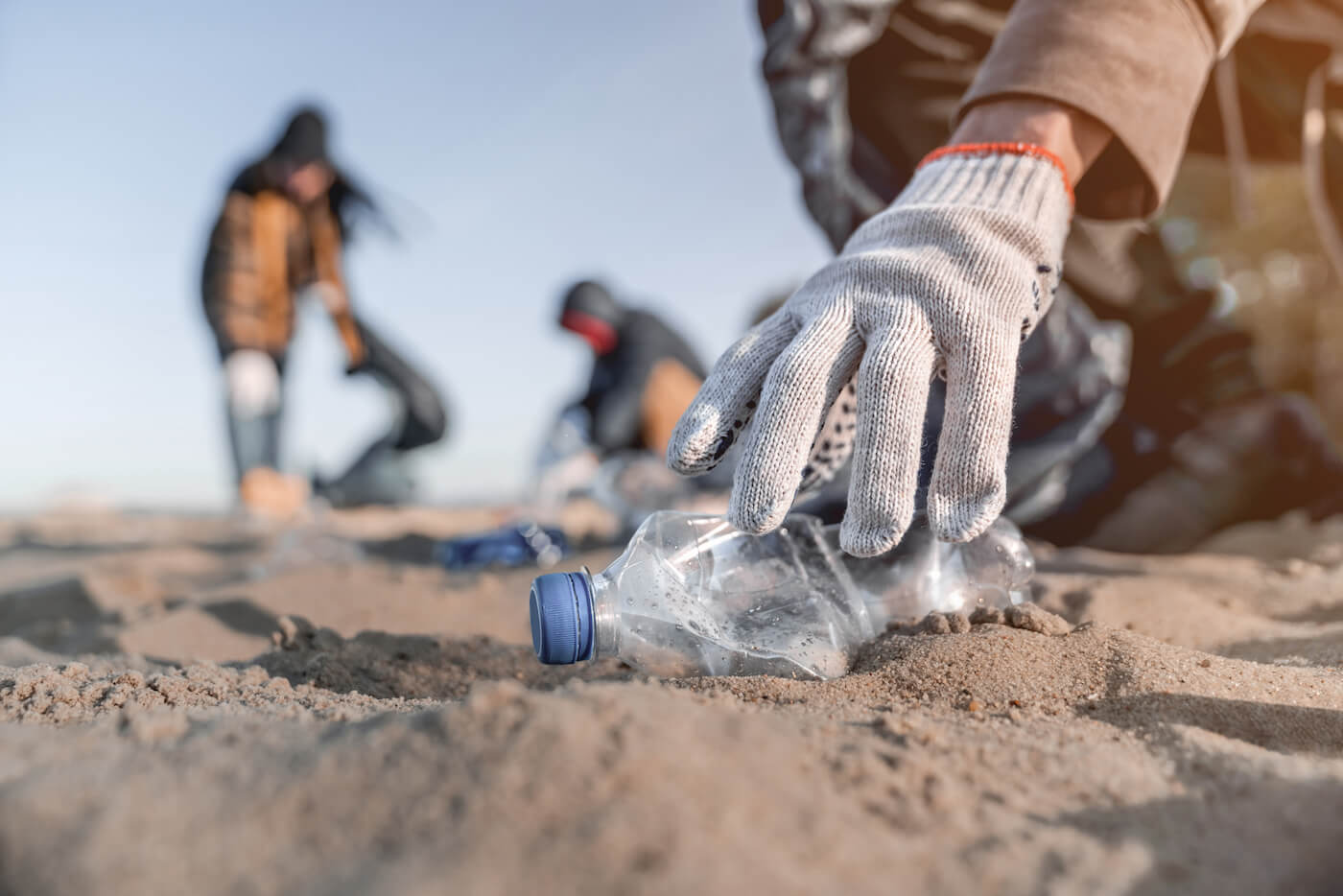 写真:砂浜に落ちているプラスチックごみを拾う人々
