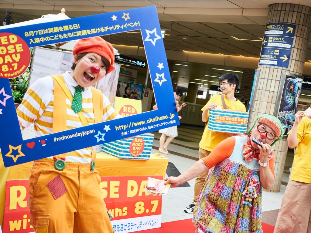 写真：「RED NOSE DAY with CliniClowns」でのチャリティイベントで、記念写真を撮るクリニクラウンと、それを楽しむ参加者の子ども