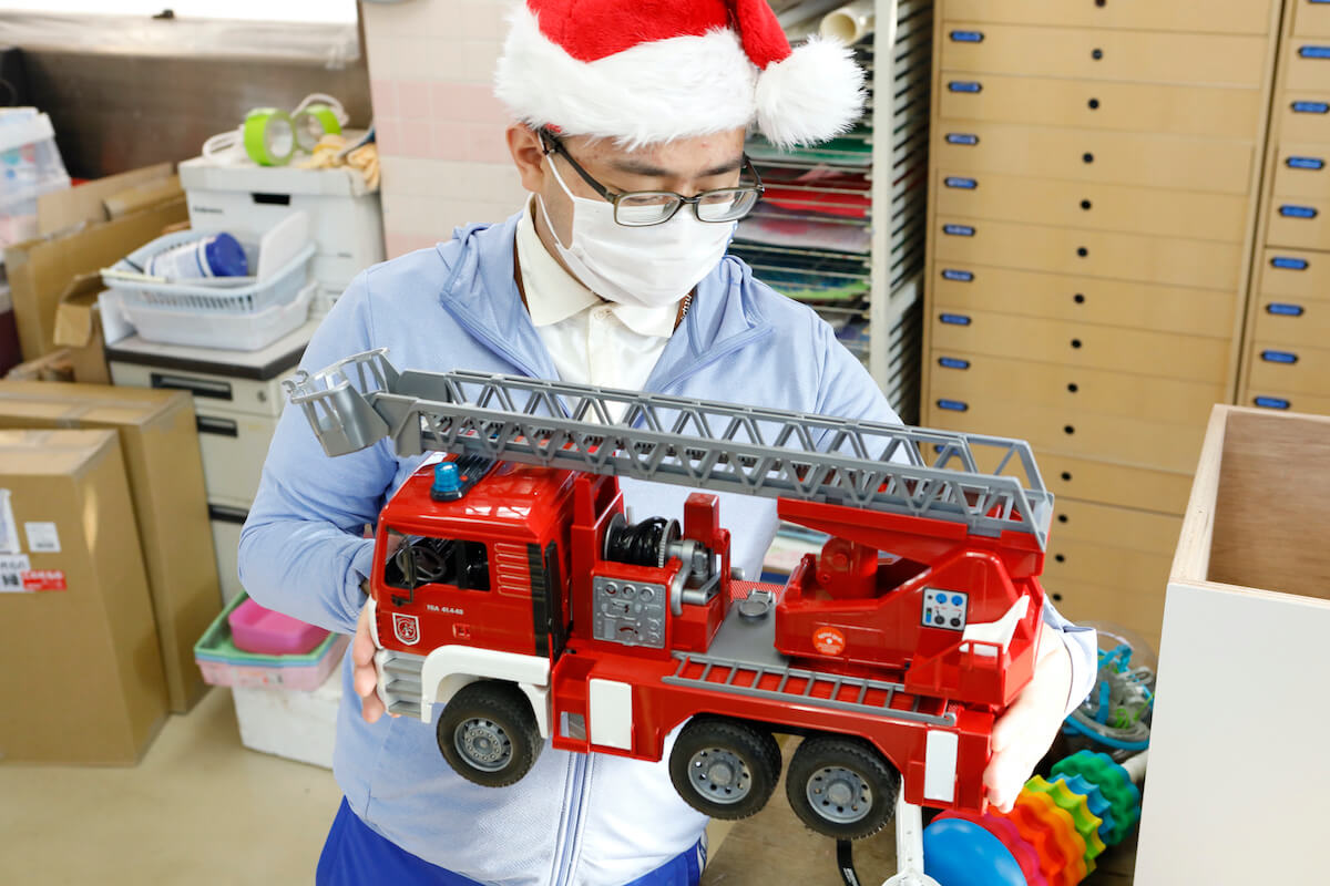 写真：消防車のおもちゃを手に持つ松田さん