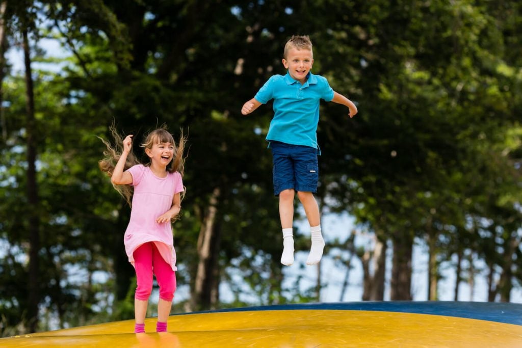写真:自然の中に設置されたトランポリンの上で、楽しそうに飛び跳ねる子どもたち