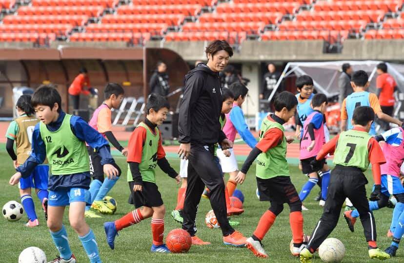 写真：フィールドで、大勢の子どもたちにサッカーを指導する巻さん