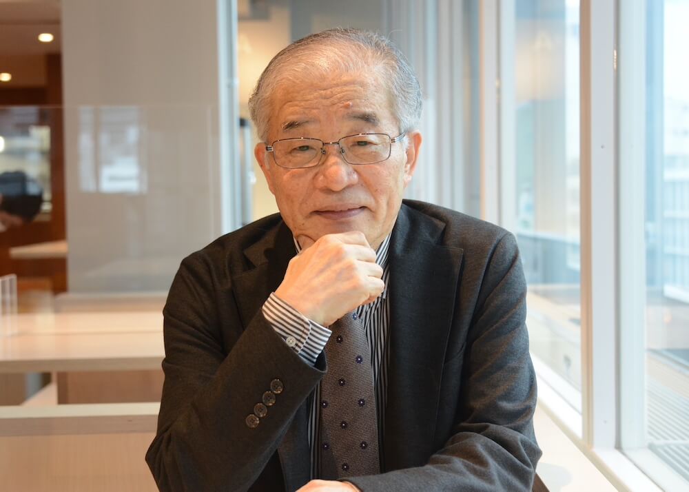 写真:顎に手をすえて微笑む宮崎さん