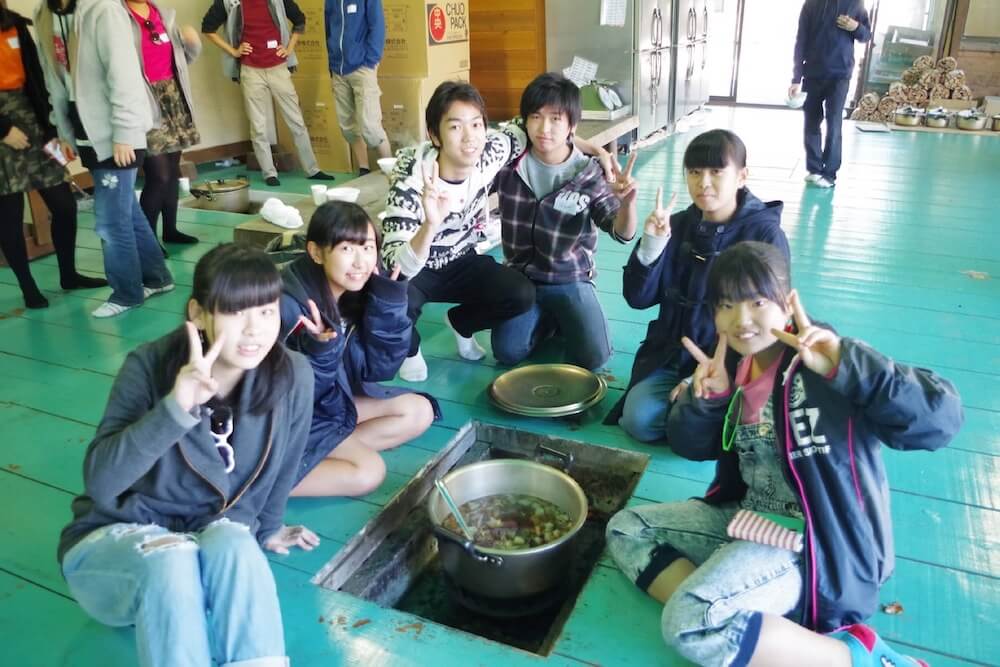 写真：屋内で行われた芋煮会で記念撮影する中学生たち