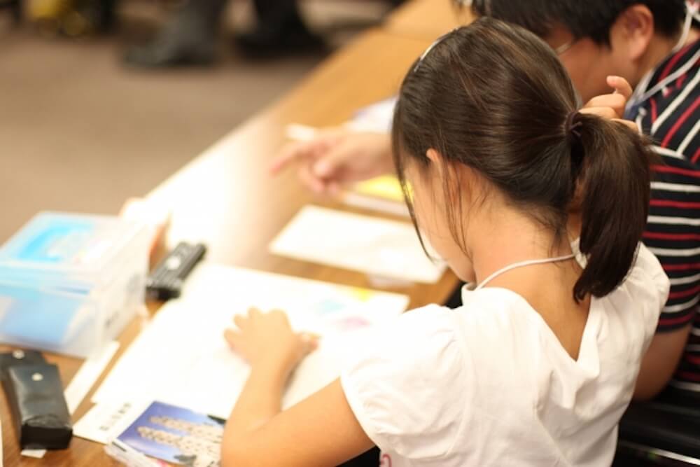 写真：塾で講師に勉強を教わる子ども