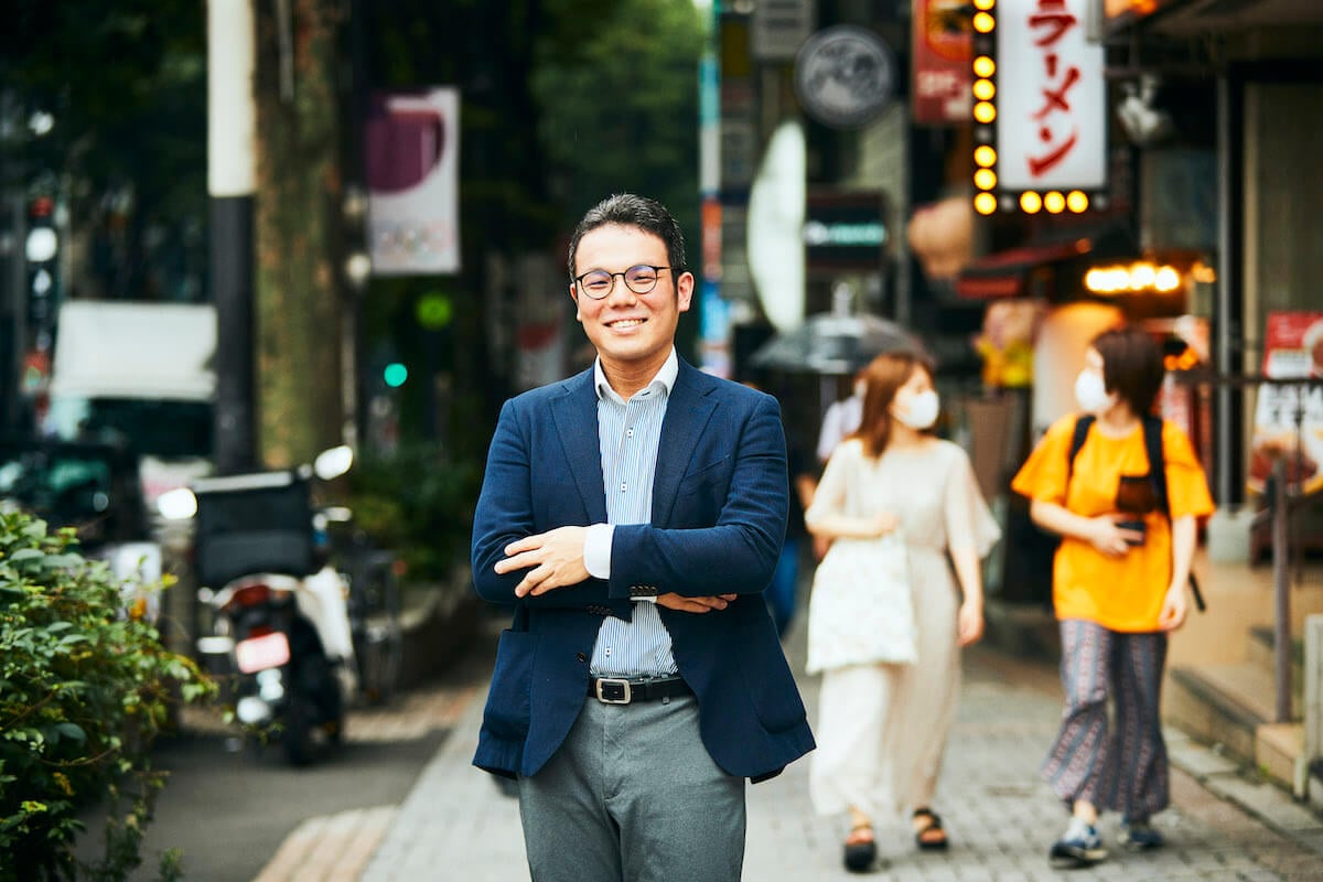 写真：雑踏の街中に立つOVA代表の伊藤次郎さん