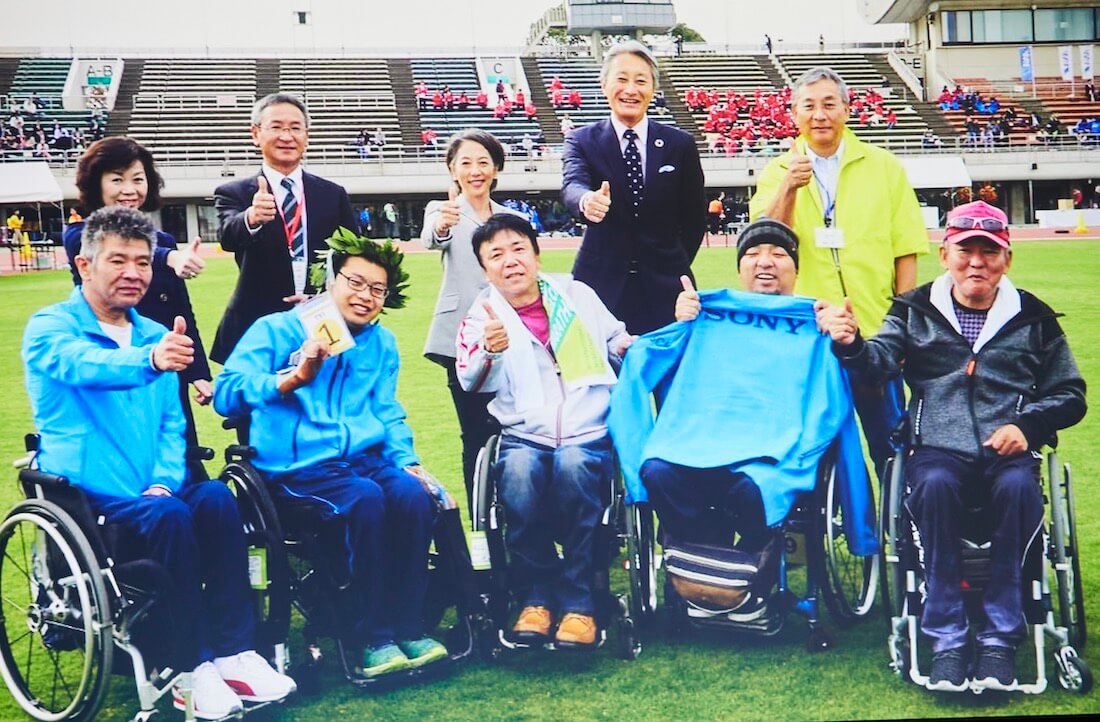 写真：大分国際車いすマラソンの会場となった競技場で記念撮影するソニー・太陽の社員と平井一夫さんを含む経営陣