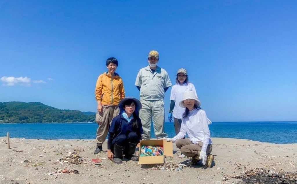 写真：海岸で集めた海ごみを囲むボランティアの皆さん（5人）