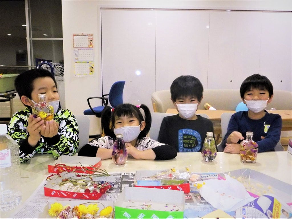 写真:子どもたちが手作りしたボトルフラワーを持って笑顔で並んでいる様子