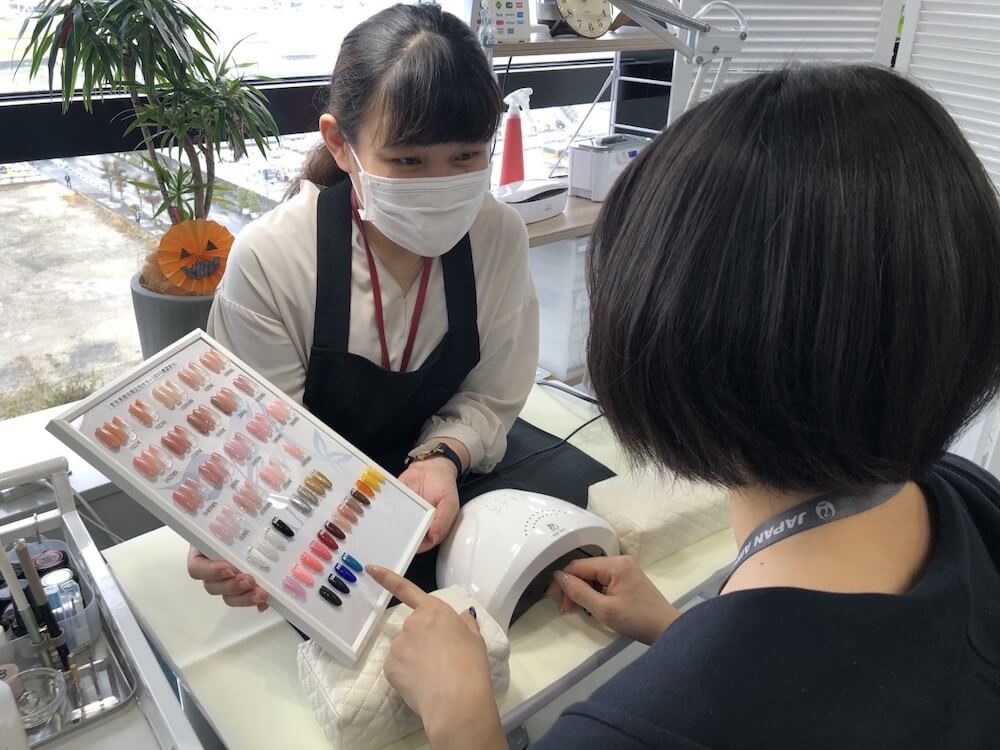 写真： JALグループの写真のネイルのカラーを確認する池田さん