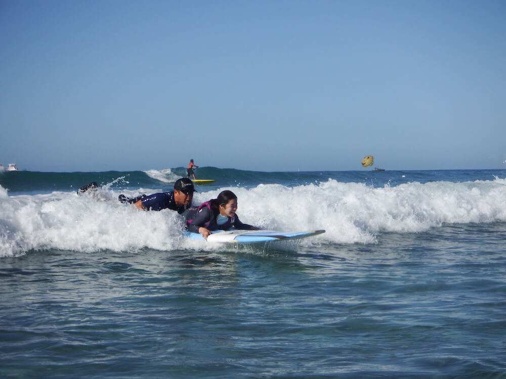 写真：インストラクラーと一緒にサーフィンを楽しむ障害のある子ども