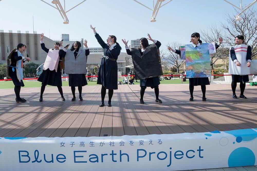 写真：屋外ステージの上で歌って踊りメッセージを届ける女子高生たち