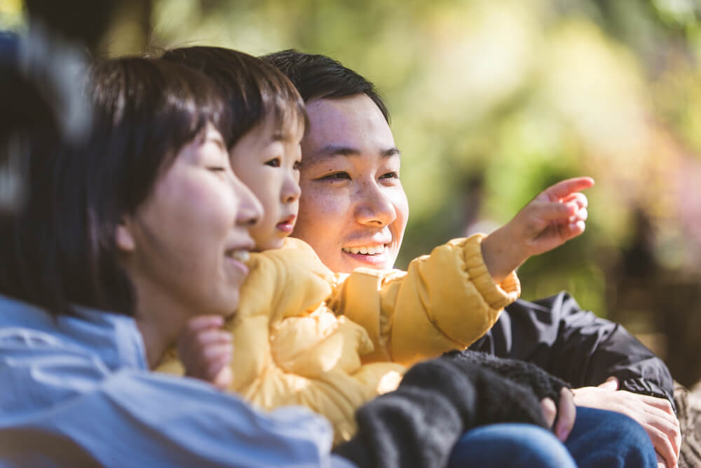 写真：遠くを指差す幼子と、幼子を抱く両親