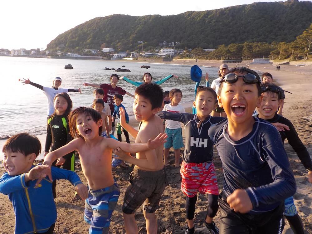 写真:海岸を駆けるたくさんの子どもたちと、それを見守るスタッフ
