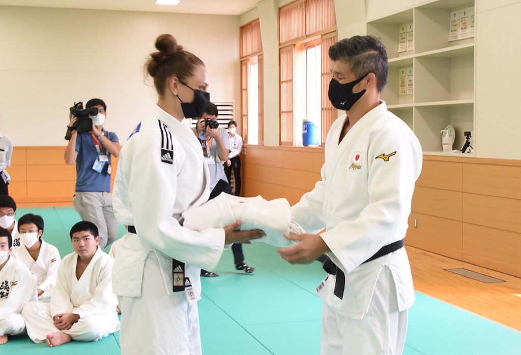 Photo of Kosei Inoue presenting a recycled judogi to one of the Ukrainian judoka