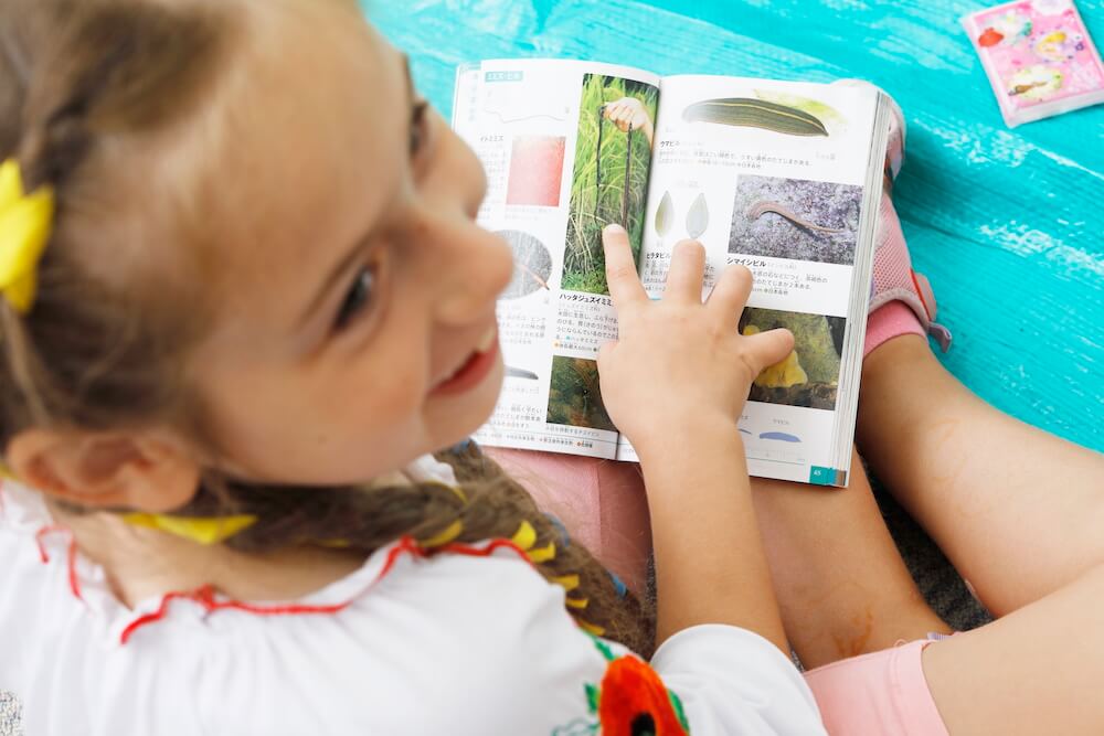 Photo of Ms. Muliavka’s elder daughter looking at a book about Japanese plants and animals