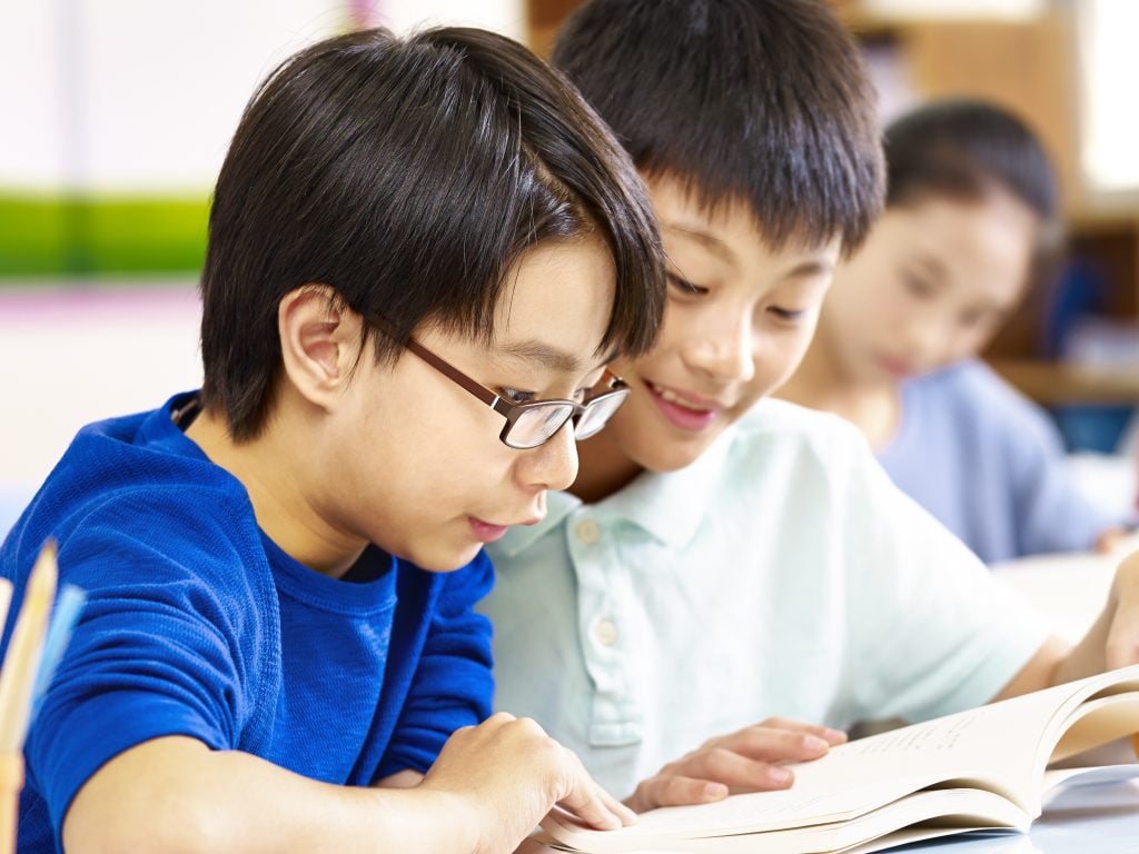 写真:友達の勉強をサポートする小学生の子ども