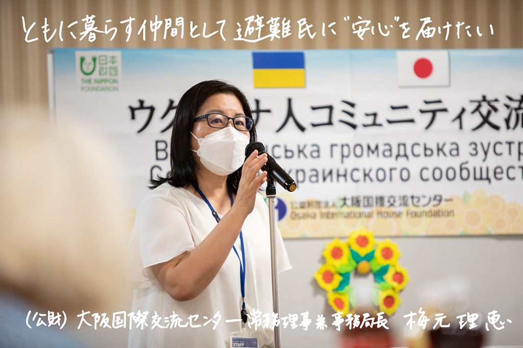 写真：（公財）大阪国際交流センター 常務理事兼事務局長 梅元理恵さん。画面上側に「ともに暮らす仲間として避難民に“安心”を届けたい」の文字。