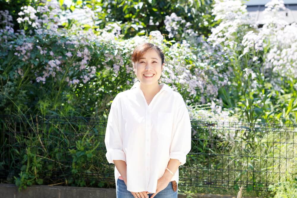 写真：きれいなお庭を背景にカメラに笑顔を向ける橋田さん