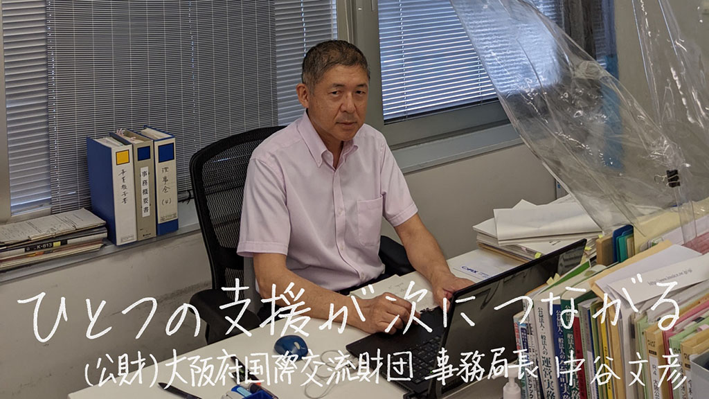 写真:公益財団法人大阪府国際交流財団 事務局長の中谷文彦さん。画像下側に「ひとつの支援が次につながる (公財)大阪府国際交流財団 事務局長 中谷文彦」の文字。