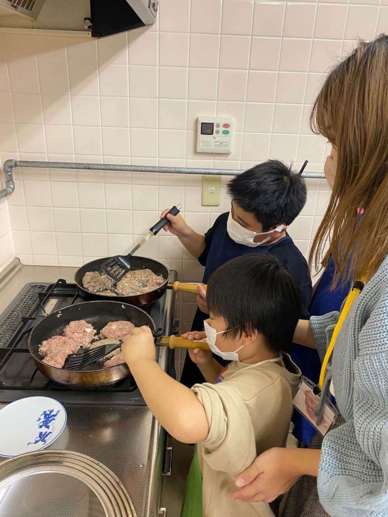 写真：キッチンでハンバーグを焼く子どもたちとスタッフ