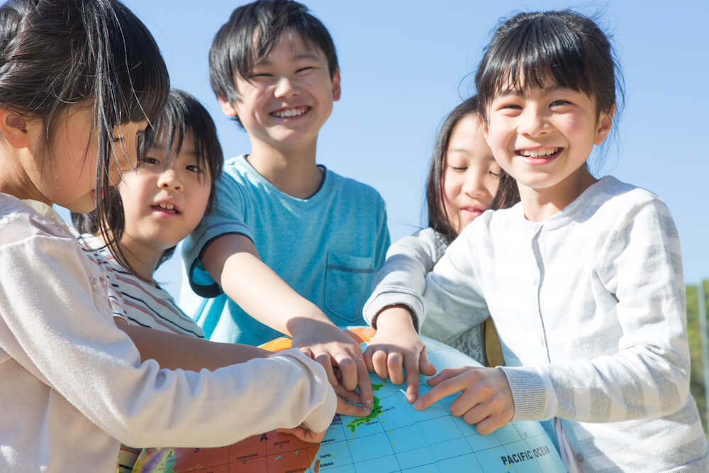 写真：地球儀の日本を指す複数の子どもたち