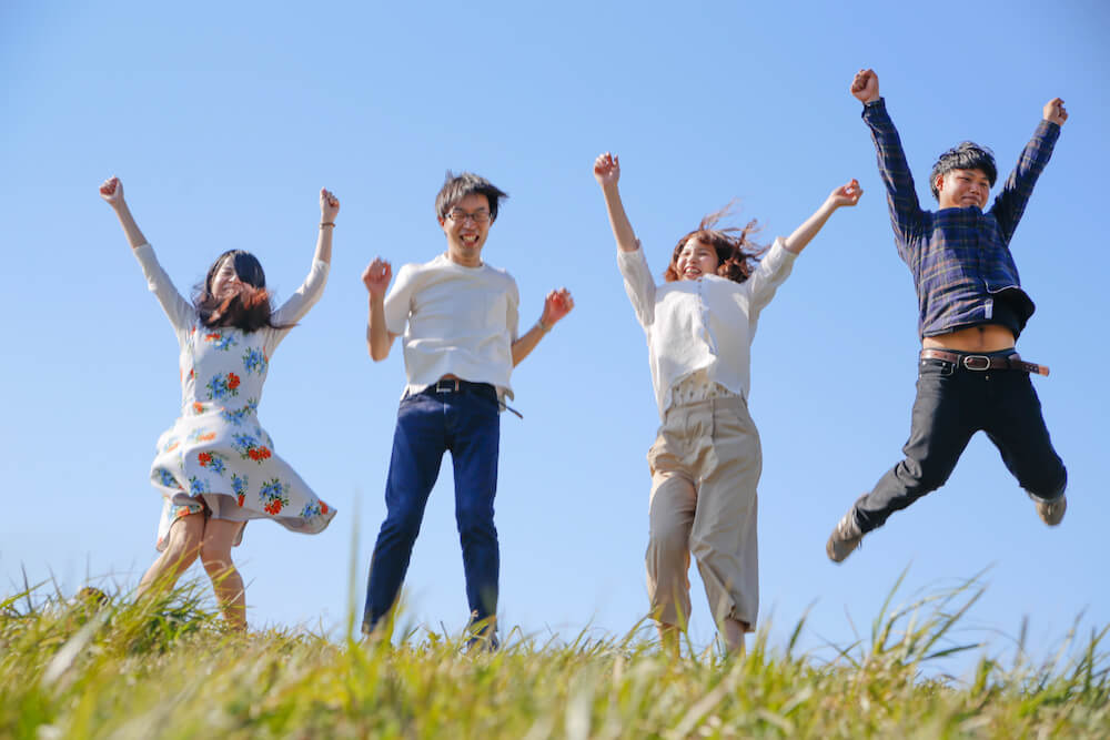 イメージ写真：草原で元気よくジャンプする子どもたち