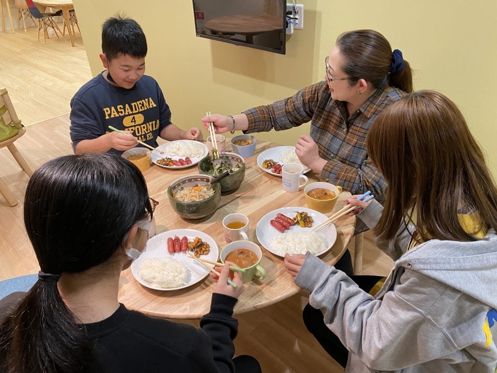 写真:食卓を囲んで子どもたちとスタッフが食事を取る様子
