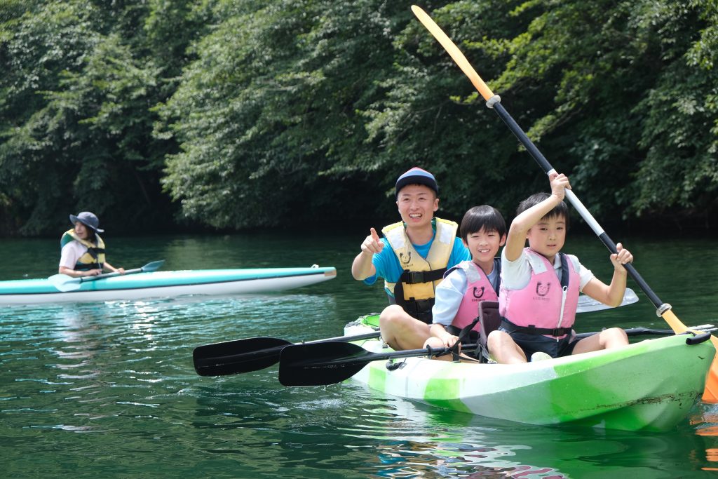 写真：川でカヌーを漕ぐ子どもたちとスタッフ