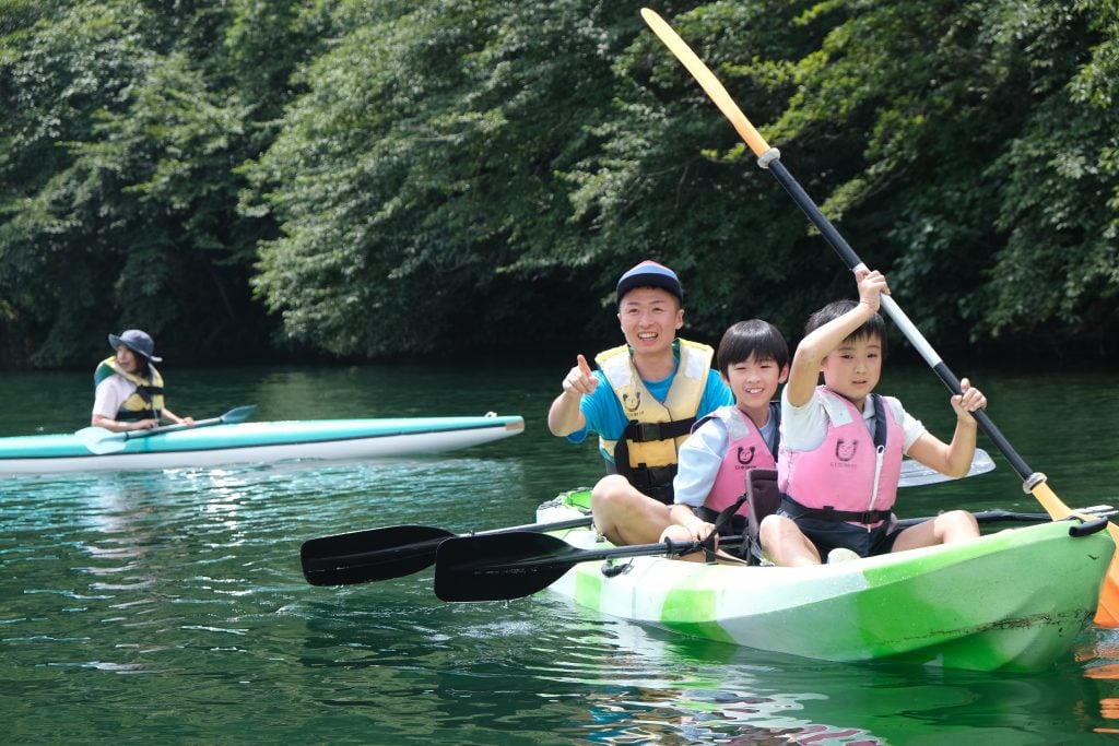 写真:川でカヌーを漕ぐ子どもたちとスタッフ