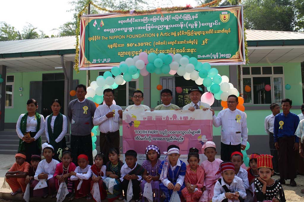 Photo of children and adults in front of a newly built school in Myanmar