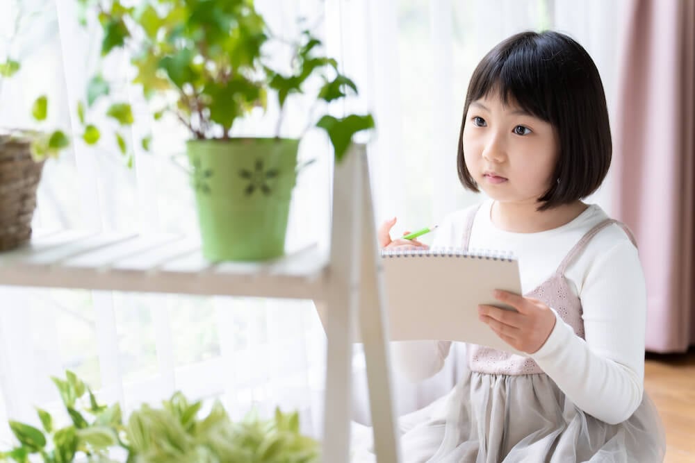 イメージ写真:自宅で植物をじっくり観察しながらノートにまとめる子ども